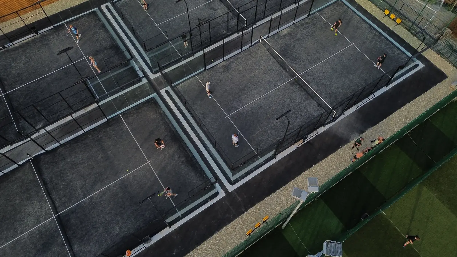 The outdoor courts at Pukka Padel Leeds at dusk, seen from above, with players on court.