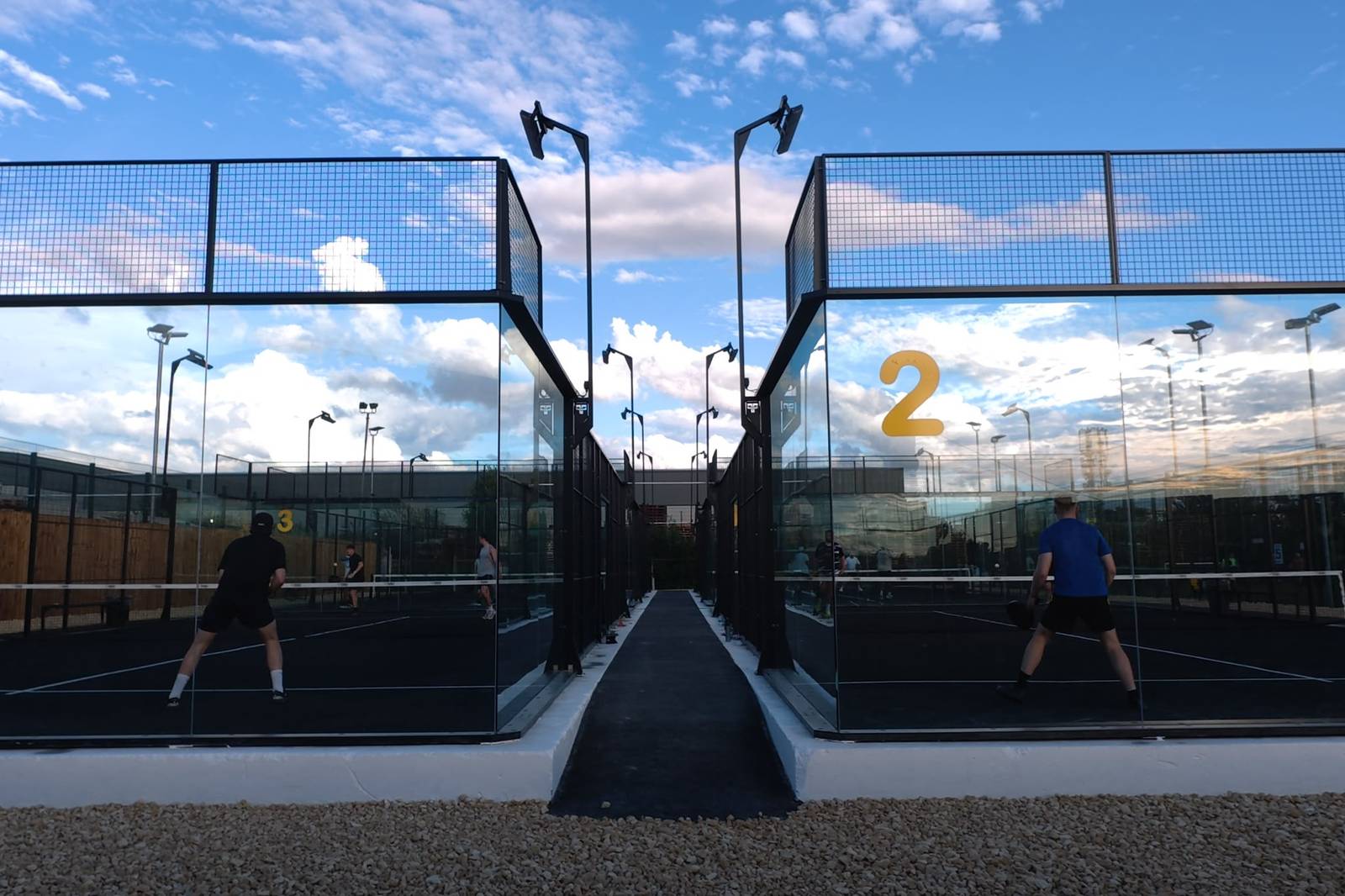 Two players walking towards the outdoor courts at Pukka Padel Leeds.