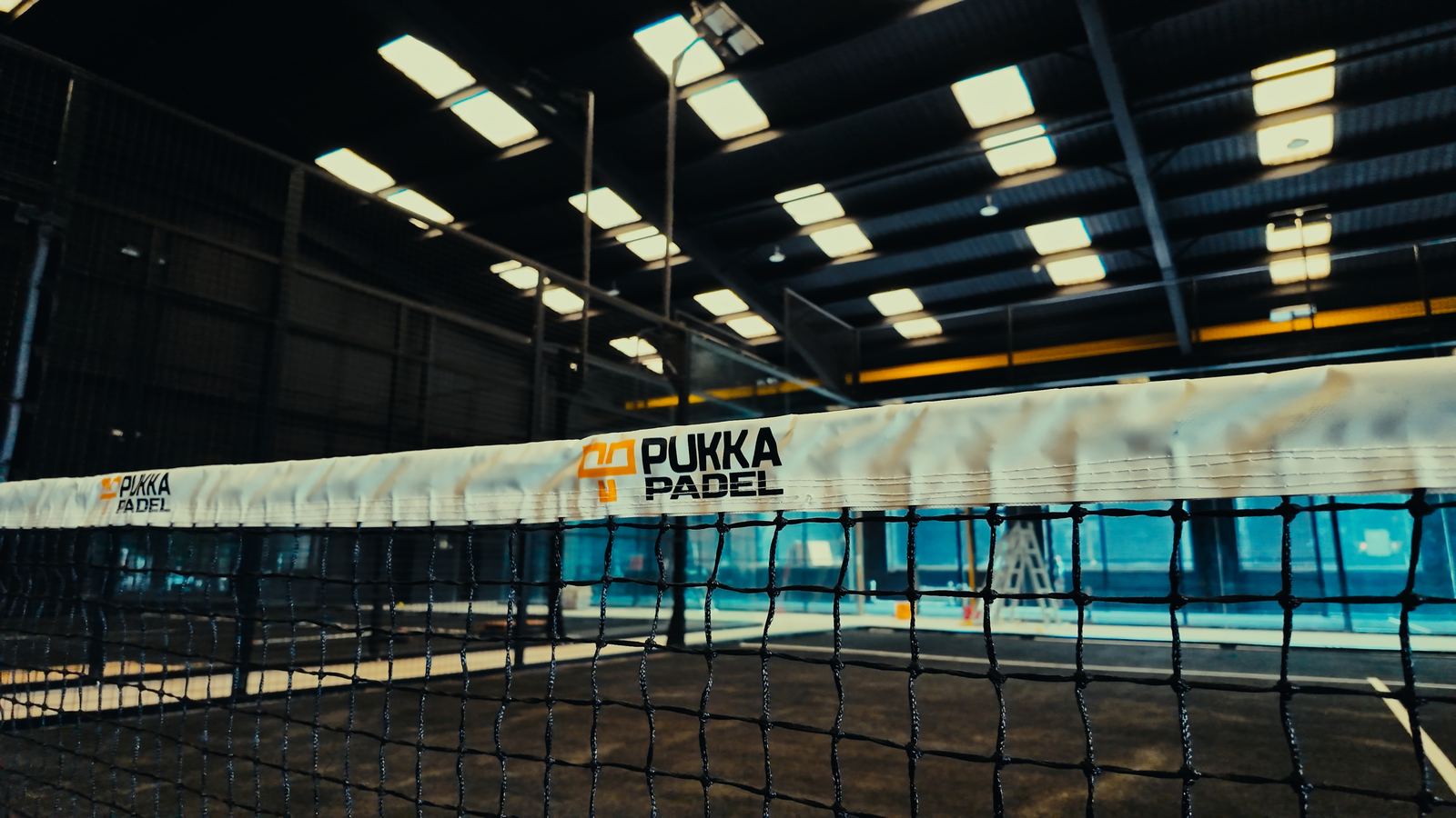 An indoor Pukka Padel court in Kidderminster with a branded net tape.