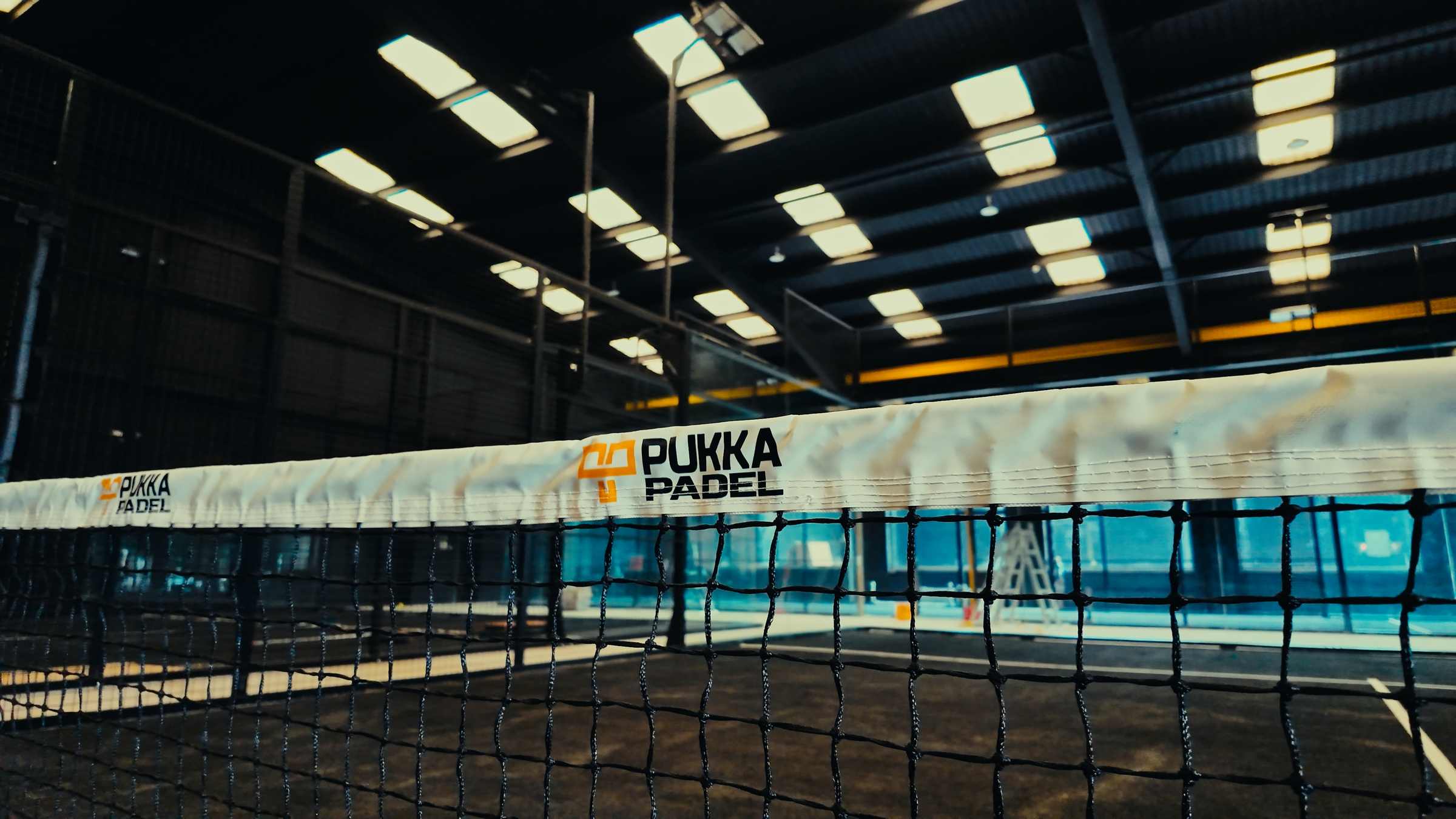 An indoor Pukka Padel court in Kidderminster with branded net tape.